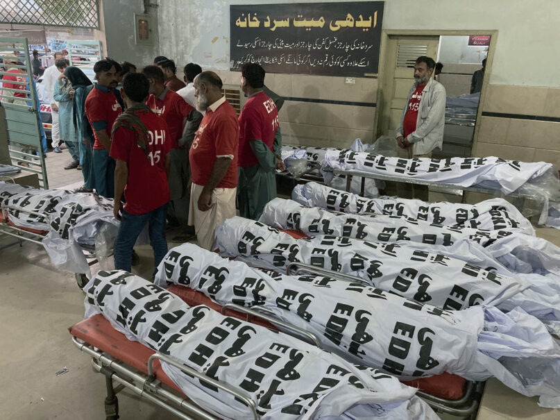 Volunteers gather beside the bodies of the victims of a bus crash, at a morgue in Karachi, Pakistan, Thursday, April 11, 2024. A Pakistani official says a bus crash has killed and  injured multiple persons in the country's southwest. (AP Photo/M. Farooq)