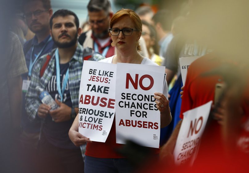 A woman holds signs about abuse during a rally outside the annual meeting of the Southern Baptist Convention at the Birmingham-Jefferson Convention Complex on June 11, 2019, in Birmingham, Ala. (RNS photo/Butch Dill)