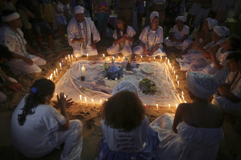 Followers of the Afro-Brazilian Candomblé faith hold a candlelit ritual before dawn on the feast day of sea goddess Yemanja in Salvador, Brazil, on Feb. 2, 2018. (AP Photo/Eraldo Peres)