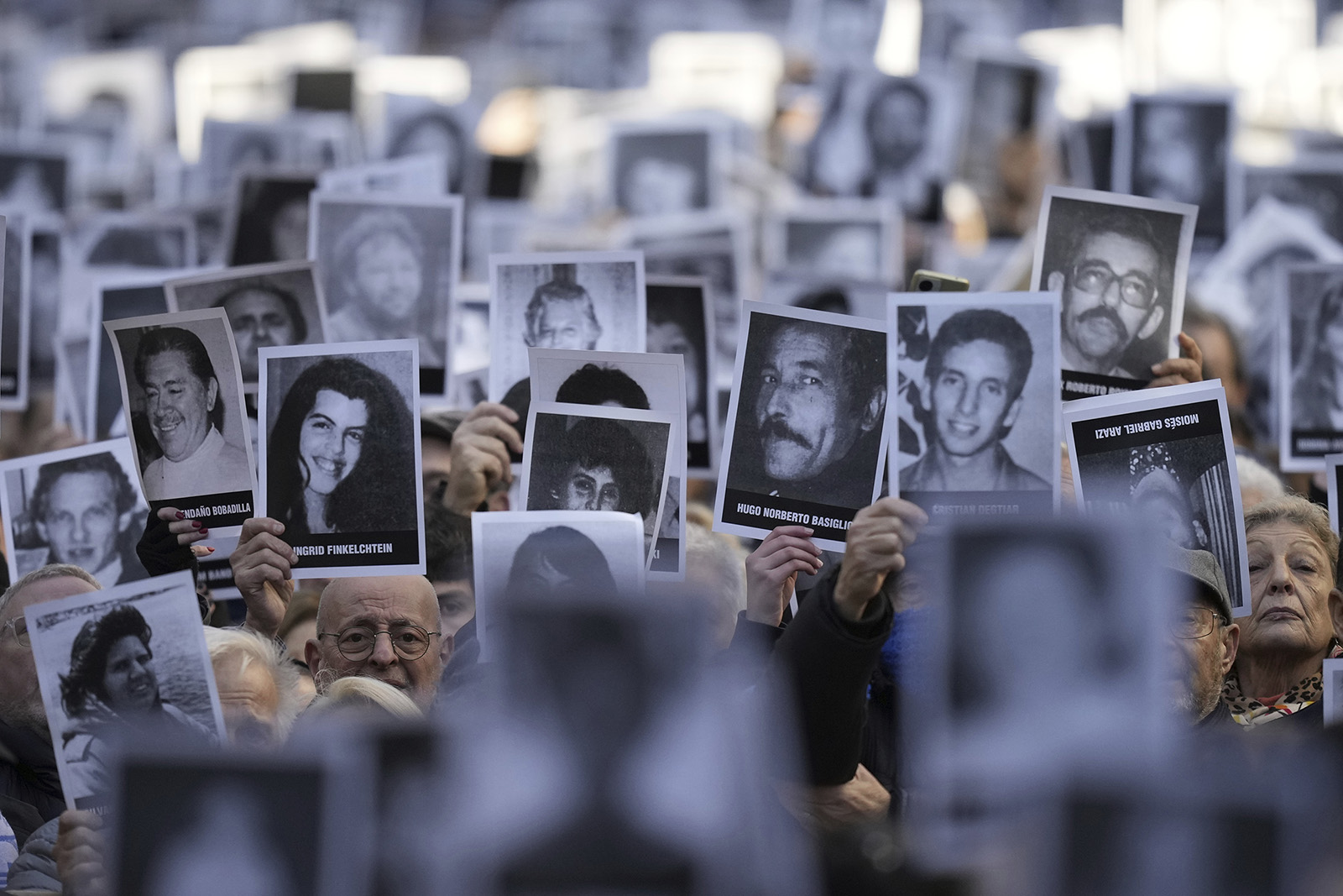 People hold photos of bombing victims in Buenos Aires, Argentina, July 18, 2024, during a ceremony marking the 30th anniversary of the bombing of the AMIA Jewish center that killed 85 people. (AP Photo/Natacha Pisarenko)