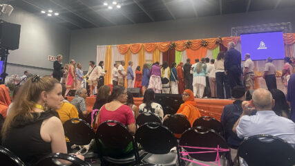 People line up on a stage to hug Amma, Wednesday, Aug. 7, 2024, at Javits Convention Center in New York. After meeting Amma, people were invited to sit and reflect on the experience, foreground. (RNS photo/Richa Karmarkar)