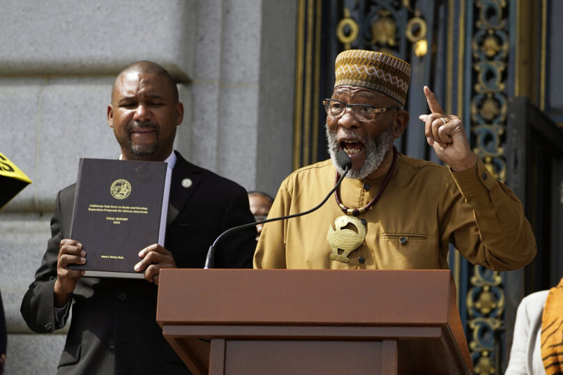 The Rev. Amos Brown speaks during a rally in support of reparations for African Americans as Supervisor Shamann Walton, left, listens outside City Hall in San Francisco, on Sept. 19, 2023. San Francisco's supervisors offered a formal apology to Black residents for decades of racist laws and policies perpetrated by the city. All 11 supervisors signed on as sponsors of an apology resolution to be voted on Feb. 27, 2024. (AP Photo/Eric Risberg, File)