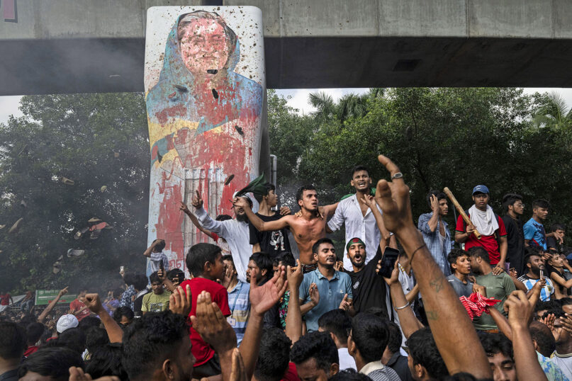 Protesters celebrate beside a defaced portrait of Prime Minister Sheikh Hasina after news of her resignation, in Dhaka, Bangladesh, Aug. 5, 2024. (AP Photo/Fatima Tuj Johora)