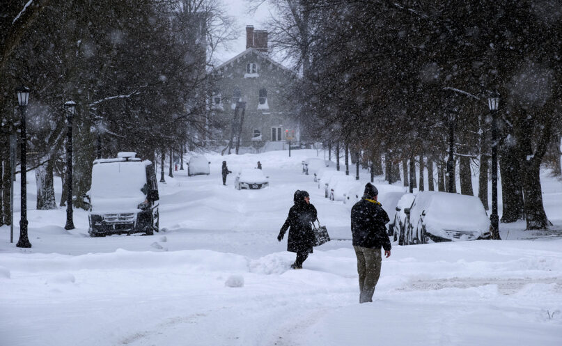 People move about the streets of the Elmwood Village neighborhood of Buffalo, New York, Monday, Dec. 26, 2022, after a massive snow storm blanketed the city. Along with drifts and travel bans, many streets were impassible due to abandoned vehicles. (AP Photo/Craig Ruttle)