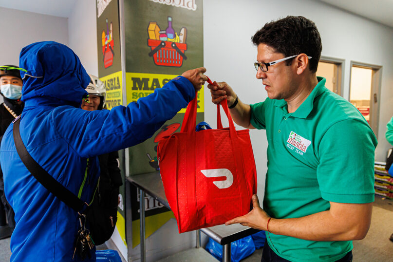 A delivery person takes a Project DASH bag from a Masbia Soup Kitchen Network team member in Brooklyn, New York. (Photo courtesy Masbia)