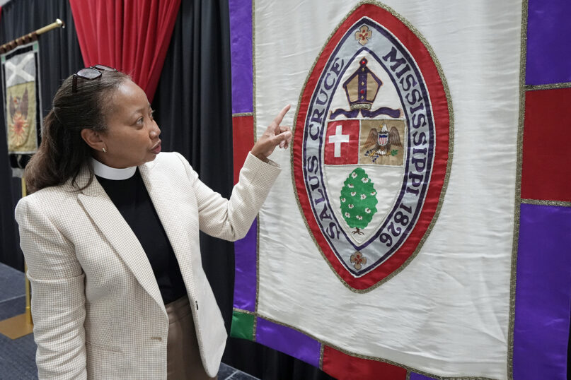 The Rev. Dorothy Sanders Wells, a native of Mobile, Ala., explains the different sections of the flag of the Episcopal Diocese of Mississippi in Ridgeland, Miss., July 19, 2024, before she is formally installed Saturday as the first woman and first Black person to hold the post of the Episcopal bishop in Mississippi. (AP Photo/Rogelio V. Solis)