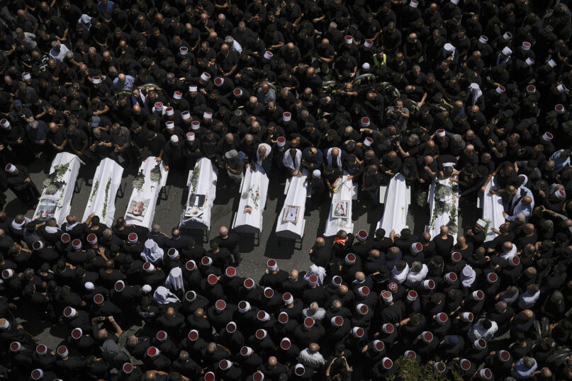 Mourners from the Druze community surround the bodies of some of the 12 children and teens killed in a rocket strike at a soccer field, in the village of Majdal Shams at the Israeli-controlled Golan Heights, July 28, 2024. (AP Photo/Leo Correa)