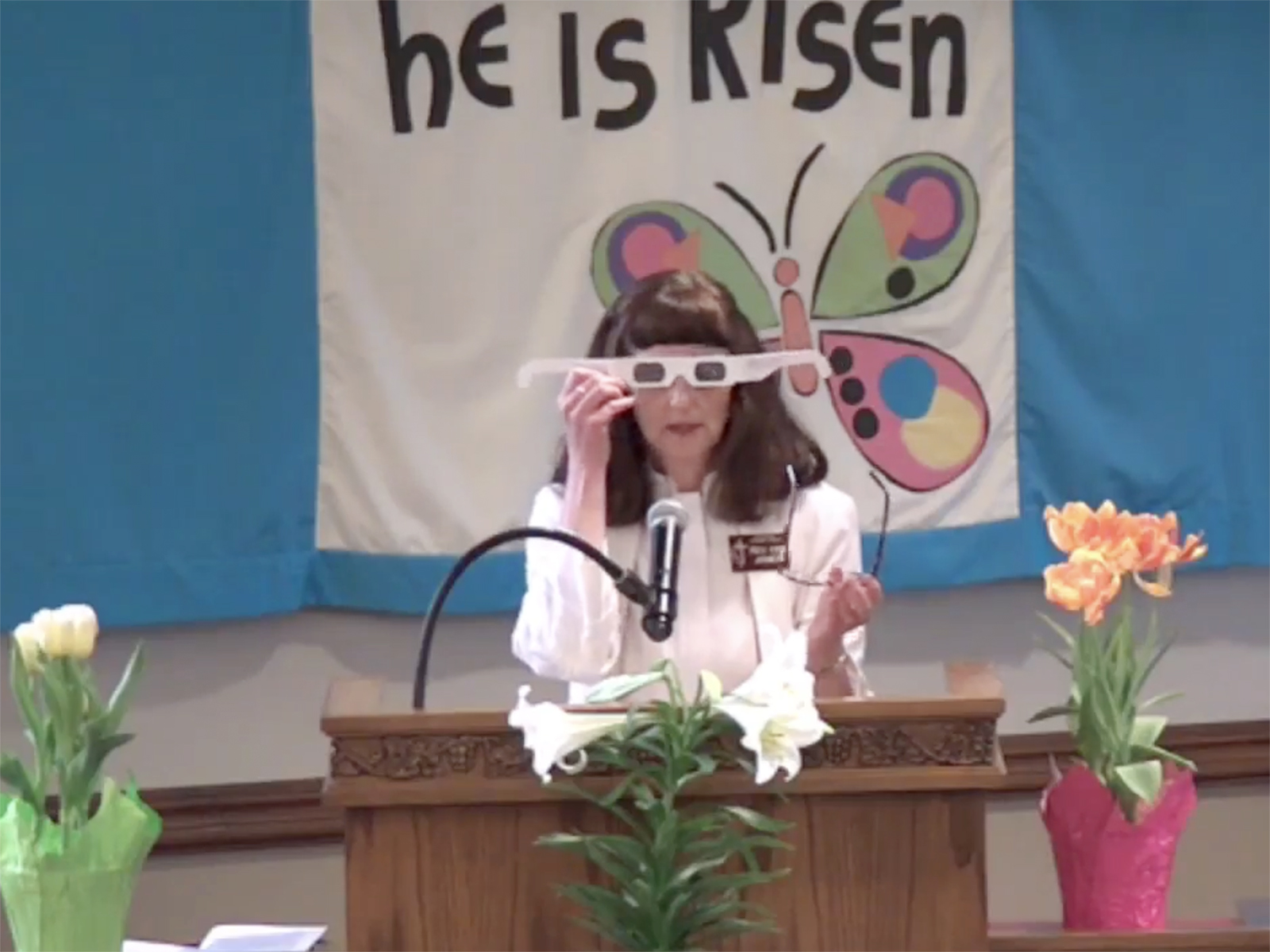 The Rev. Kim James demonstrates using solar eclipse glasses during an Easter Sunday service at Ogden First United Methodist Church in Marriott-Slaterville, Utah. (Video screen grab)