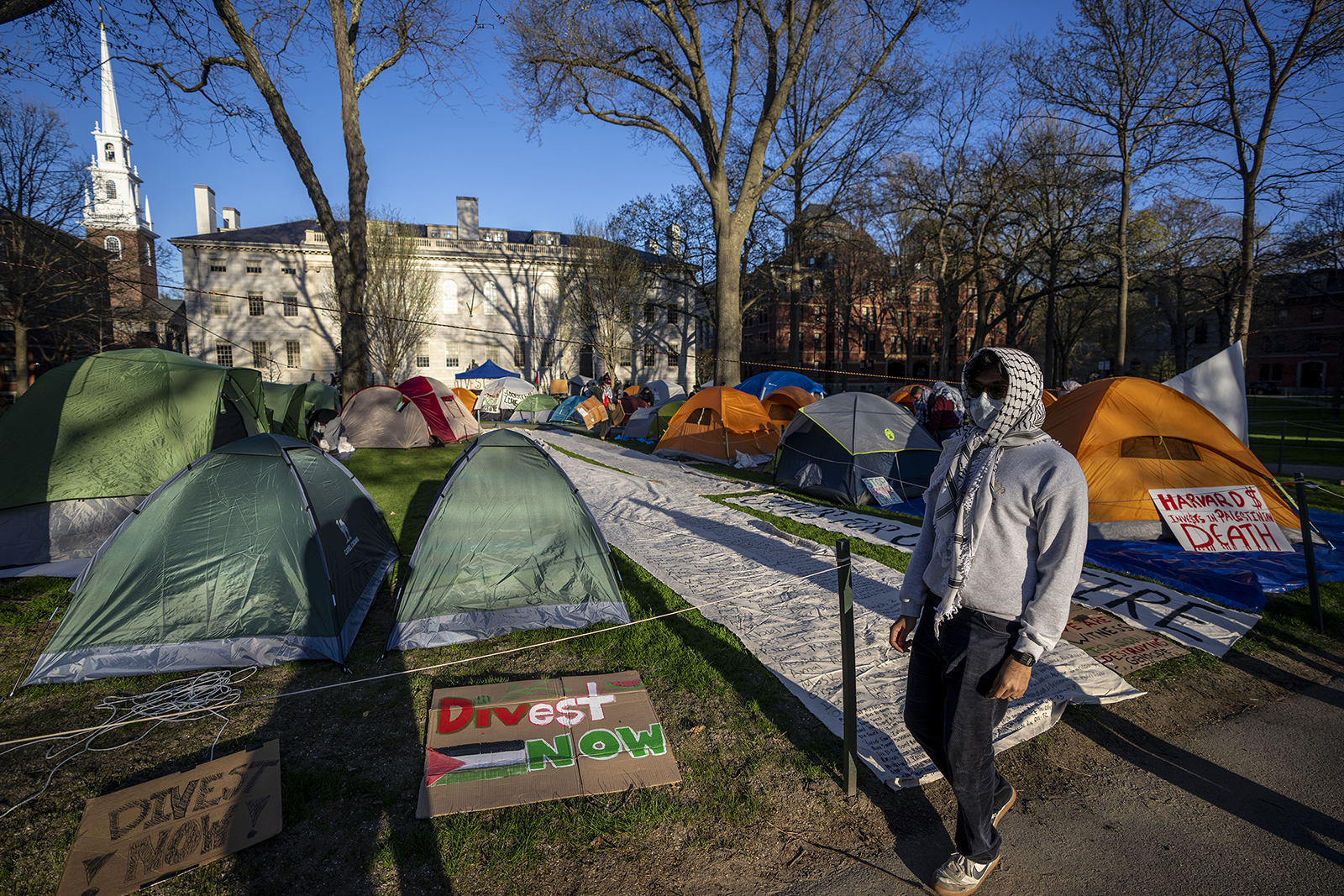 A student protester against the war in Gaza walks past tents and banners in an encampment in Harvard Yard, at Harvard University in Cambridge, Mass., on Thursday, April 25, 2024. (AP Photo/Ben Curtis)