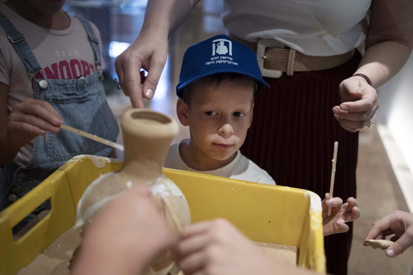 Ariel Heller, 4, helps to glue a broken clay jar during a special tour with his family after he accidentally broke another jar at the Reuben and Edith Hecht Museum in Haifa, Israel, Aug. 30, 2024. The boy, who accidentally broke a rare 3,500-year-old jar in the museum, has been forgiven and invited back, as curators hope to turn the disaster into a teachable moment. (AP Photo/Maya Alleruzzo)