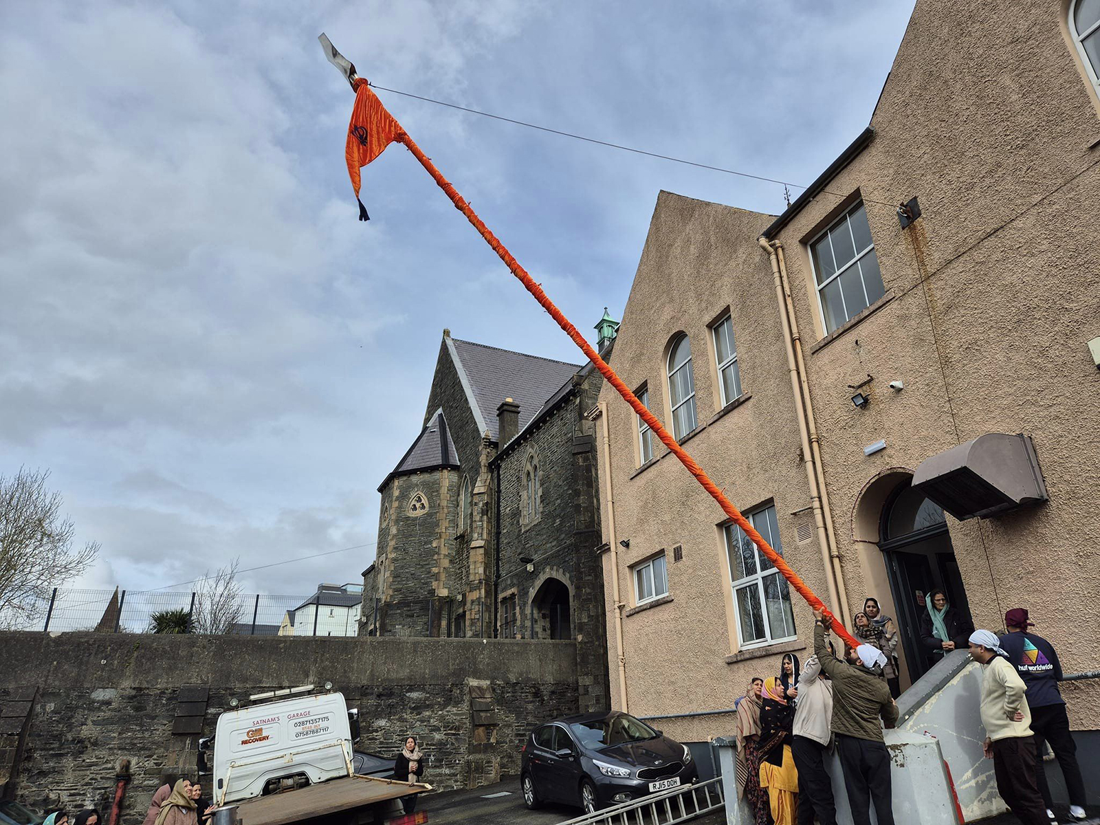 A group of Derry Sikhs raise the Nishan Sahib flag ahead of the reopening of the local gurdwara in Londonderry, Northern Ireland, March 24, 2024. (Photo courtesy Amerjit Singh)