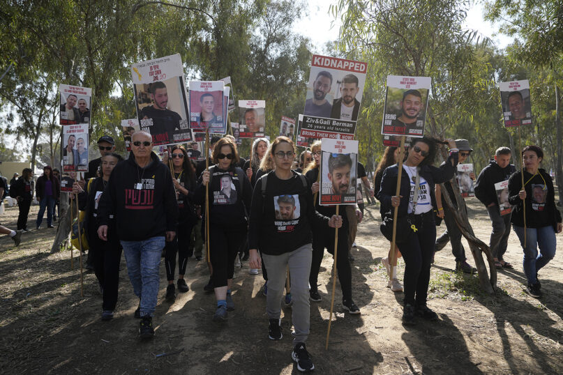 Freed hostage Sharon Alony Cunio, center, carries a poster of her husband, David Cunio, as she marches with other families of hostages held by Hamas in the Gaza Strip, in Re’im, southern Israel, as they begin their march to Jerusalem calling for the release of hostages, Feb. 28, 2024. They began the four-day march at the site where hundreds of revelers at the Nova music festival were killed or captured by Hamas on Oct. 7, 2023. (AP Photo/Tsafrir Abayov)