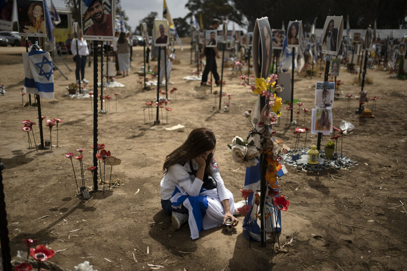 A woman sits on the ground as she attends commemorations of Israel’s annual Memorial Day, at the site of the Nova music festival where revelers were killed and kidnapped in the Oct. 7 cross-border attack by Hamas militants, near the kibbutz Reim, southern Israel, May 13, 2024. (AP Photo/Leo Correa)