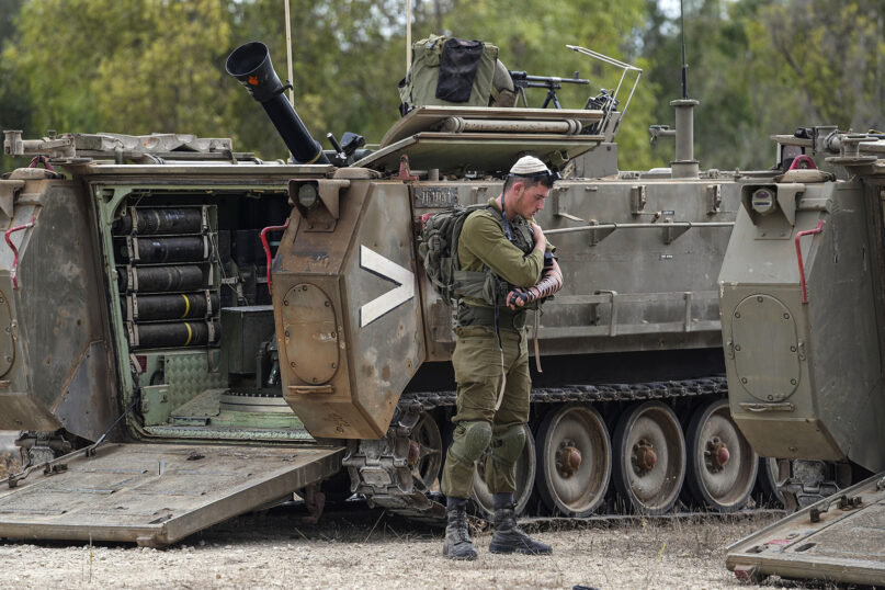 An Israeli soldier prays next to an armored personnel carrier at a staging ground near the Israeli-Gaza border, southern Israel, Oct. 9, 2023. (AP Photo/Tsafrir Abayov)