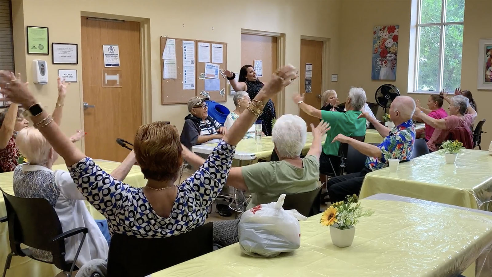 Josie Flores, standing top center, leads a laughter wellness session at an Empath Health senior center in Florida. (Image courtesy Empath Health)