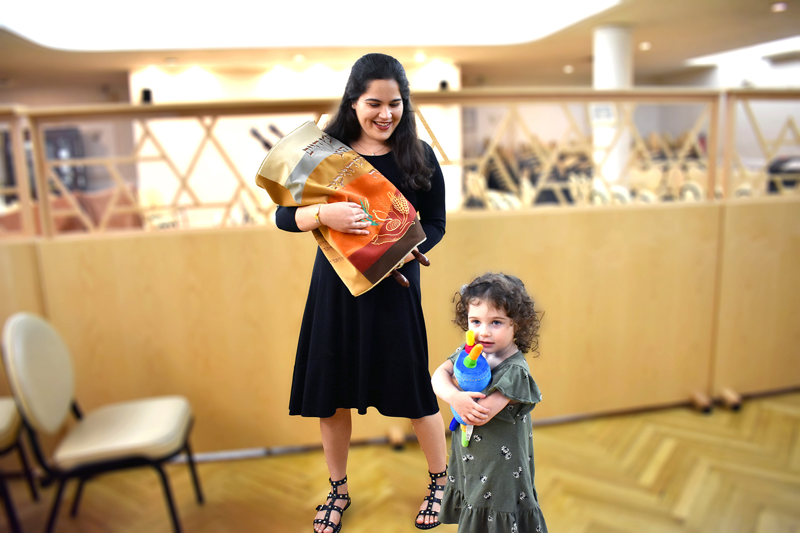 An Orthodox Jewish woman holds a Torah scroll as her daughter hugs a toy Torah. Photo by Fruma Landa, courtesy Jewish Life Photo Bank