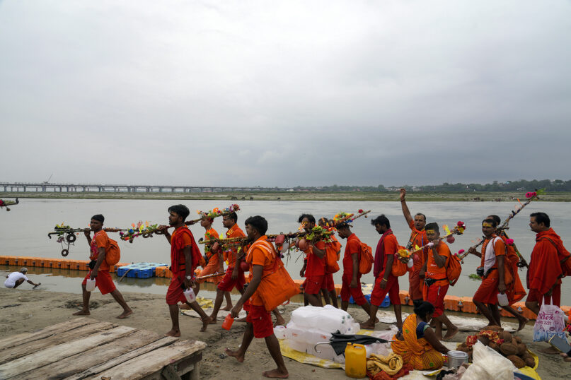 Hindu pilgrims, known as Kanwarias, walk on the banks of the Ganges River in Prayagraj, India, July 2, 2023. Kanwarias are devotees performing a ritual pilgrimage in which they walk, clad in saffron, and carrying ornately decorated canisters of sacred water from the Ganges River over their shoulders to take it back to Hindu temples in their hometowns, during the Hindu lunar month of Shravana. (AP Photo/Rajesh Kumar Singh)