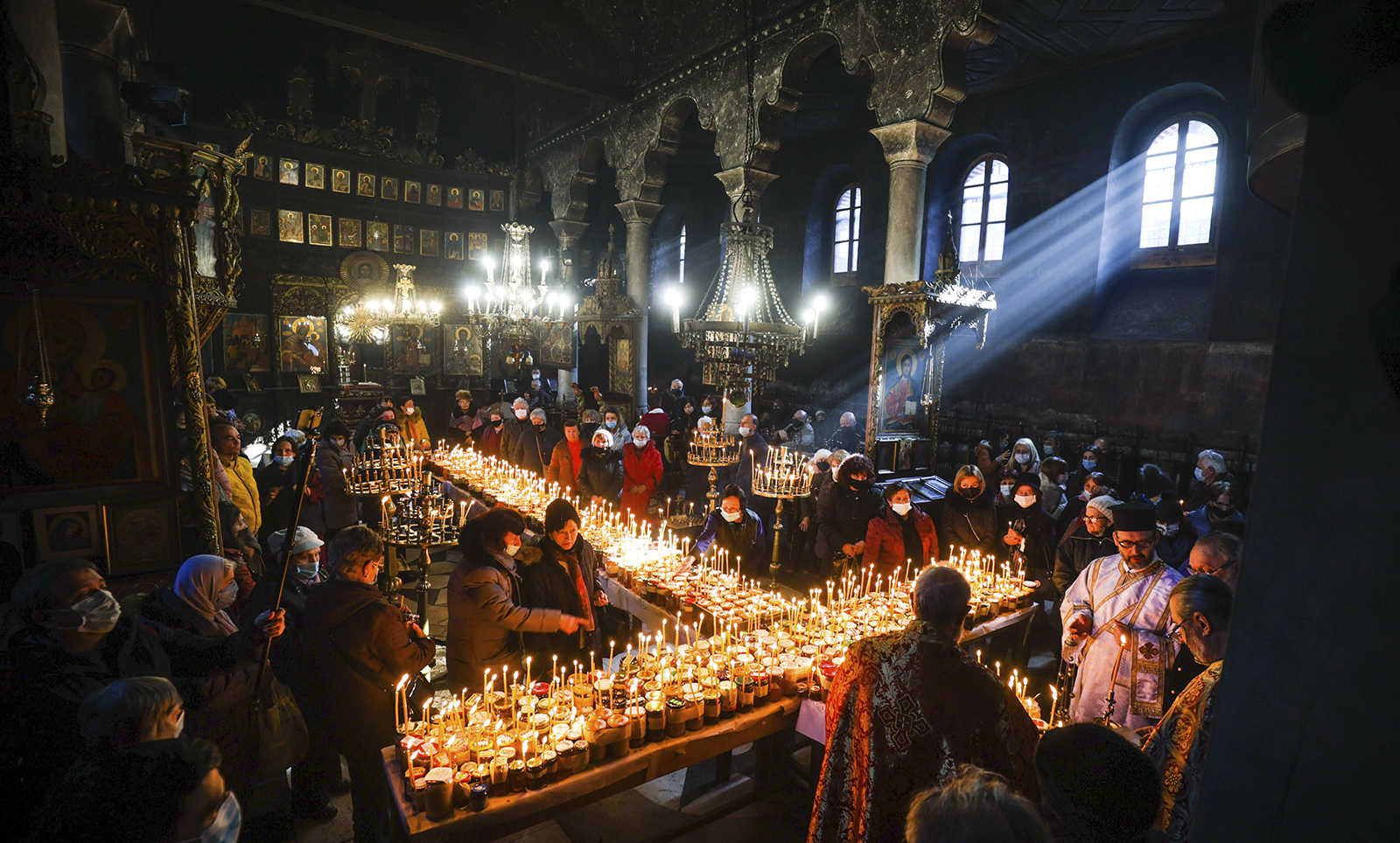 Priests read prayers in honour of St.Haralampus, as believers gather around candles stuck to jars of honey, arranged in a cross shape, during Mass for the 'sanctification of honey' at the Presentation of the Blessed Virgin Church in the town of Blagoevgrad, south of the Bulgarian capital of Sofia, Thursday, Feb. 10, 2022. The Bulgarian Orthodox Church marks the feast of St. Haralampus, the Orthodox patron saint of bee-keepers, by performing a ritual for health and rich harvest. (AP Photo/Valentina Petrova)