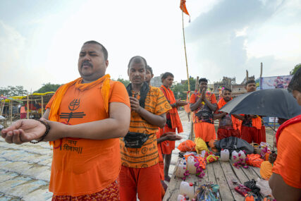 Indian Hindu Kanwarias, worshippers of Hindu God Shiva, offer prayers after taking holy dips in the Ganges River, in Prayagraj, in the northern Indian state of Uttar Pradesh, Friday, July 26, 2024. Kanwarias are young men performing a ritual pilgrimage in which they walk, sometimes hundreds of kilometers, to the Ganges River to take its sacred waters back to Hindu temples in their hometowns. During the Hindu lunar month of Shravana, hundreds of thousands of pilgrims can be seen walking the roads of India, clad in saffron, and carrying ornately decorated canisters of water over their shoulders. (AP Photo/Rajesh Kumar Singh)