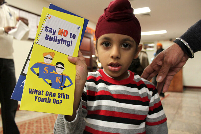 A child shows a Sikh anti-bullying brochure. (Photo courtesy of Sikh Coalition)