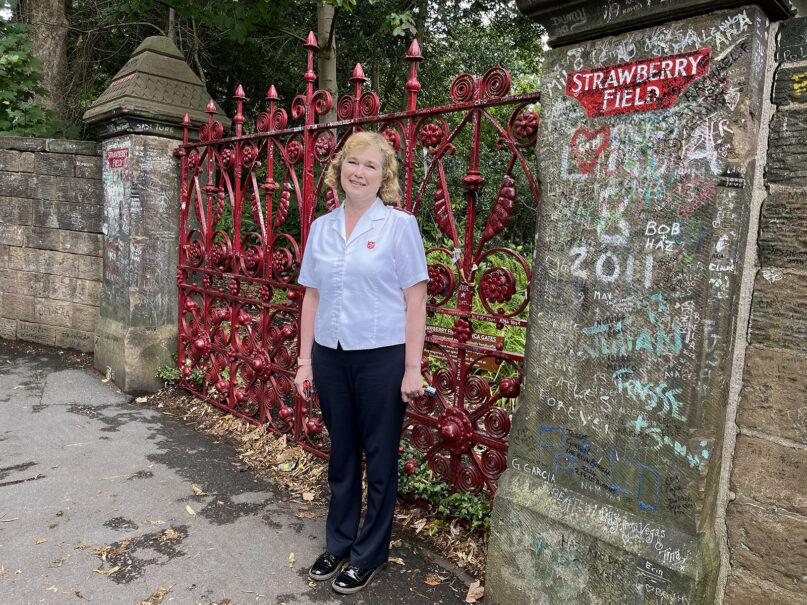 Mission director Kathy Versfeld at the famous red gates of Strawberry Field in Liverpool, England. (Photo by Catherine Pepinster)