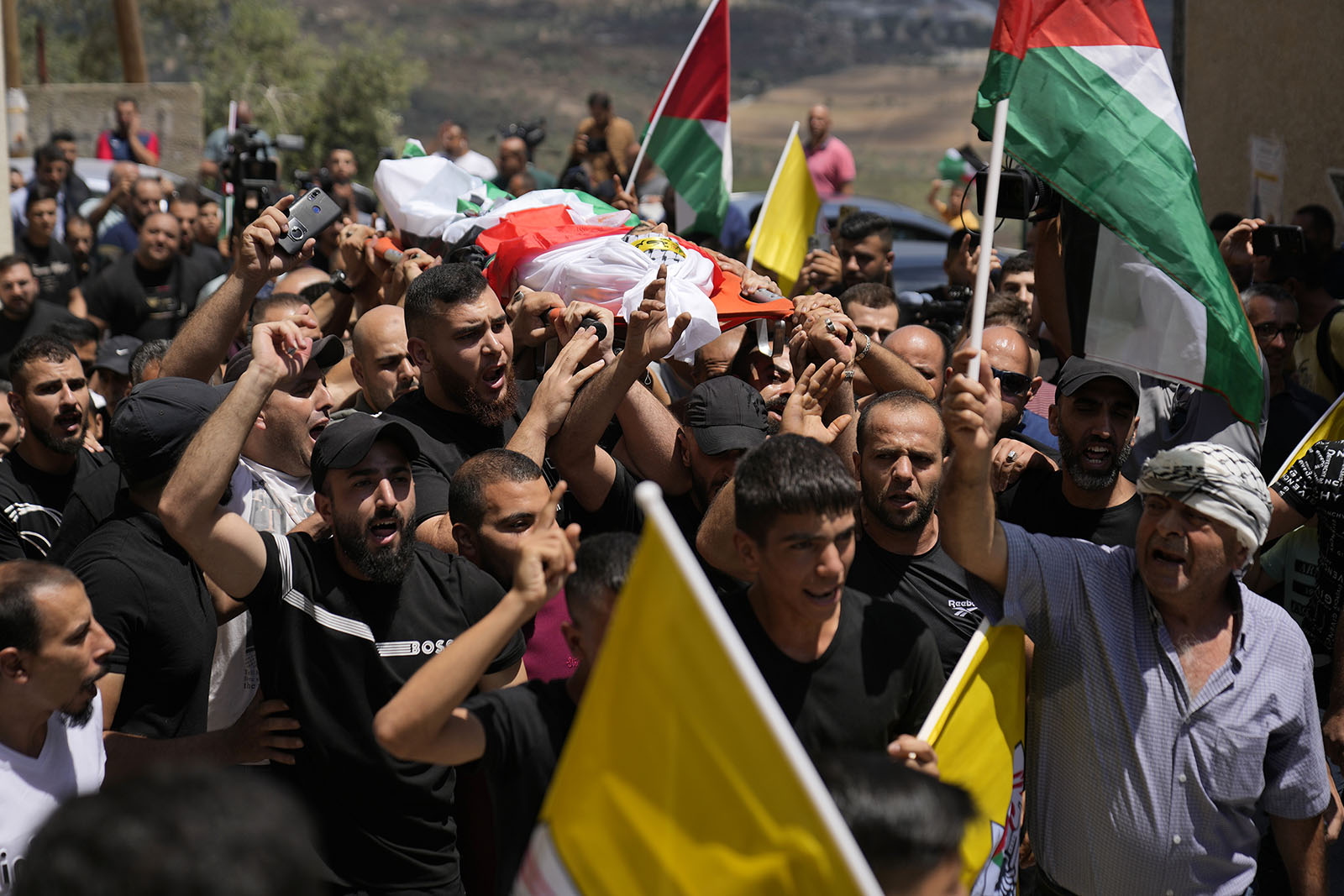 Mourners carry the body of Palestinian Rasheed Mahmoud Sadah, 23, who was killed during a rampage by Israeli settlers, during his funeral in the West Bank village of Jit, near Nablus, Friday, Aug. 16, 2024. (AP Photo/Nasser Nasser)