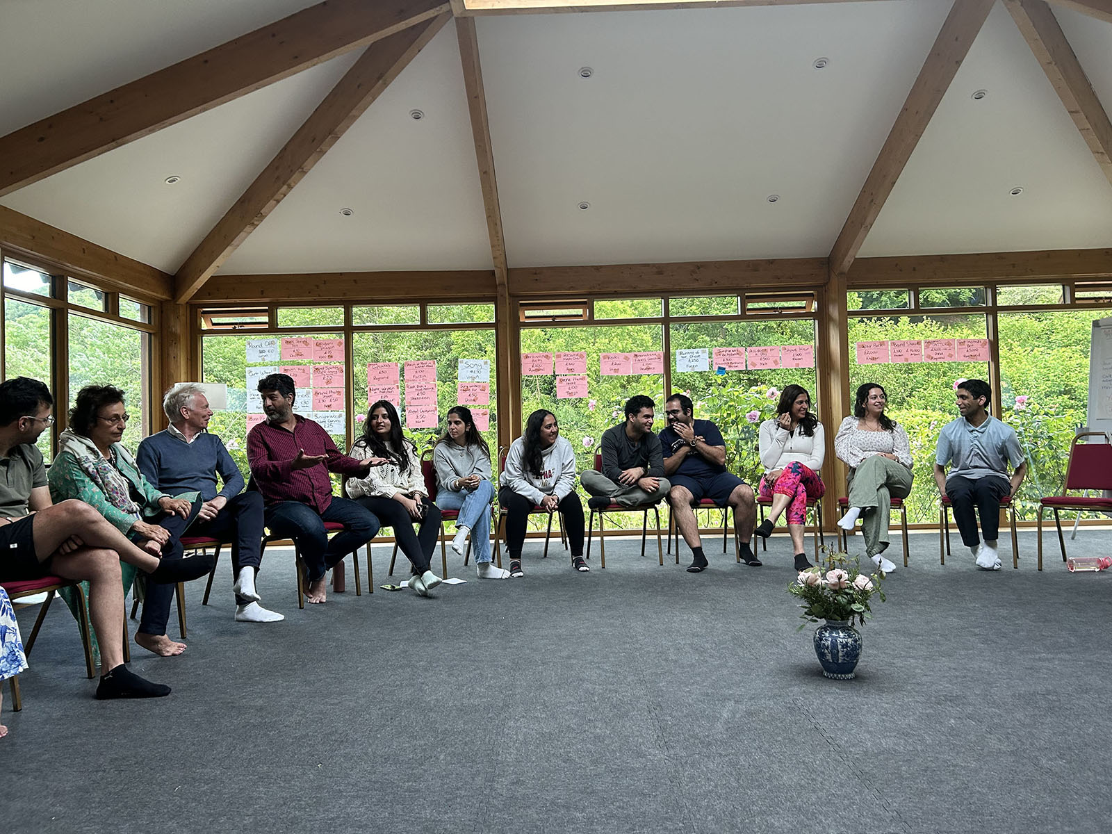 Piran Tarapore, far left, sits next to Zerbanoo Gifford in the sharing circle on May 27, 2024 at the Asha Centre in Gloucestershire, England. Behind the group is one of their initiatives to fundraise to save the Asha Centre. Each youth leader volunteered to share a talent for a raffle. (Photo by Dina Katgara)