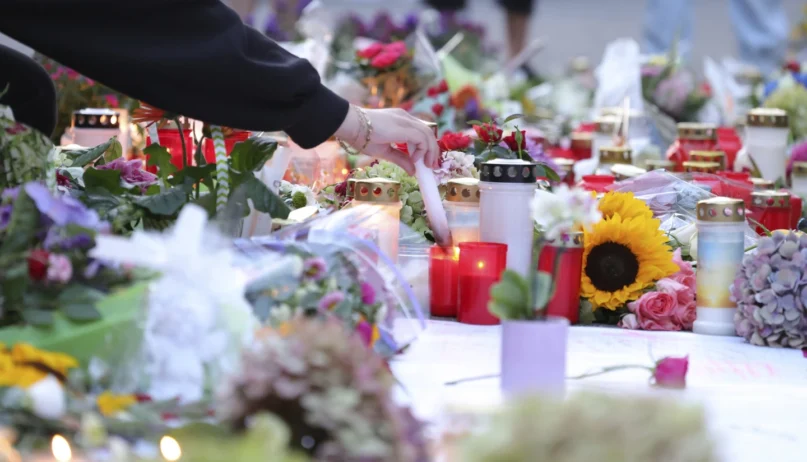 After the fatal knife attack on Friday at the Solingen city festival, people lay flowers near the scene of the crime and light candles in memory of the victims in Solingen, Germany, Sunday, Aug. 25, 2024. (Gianni Gattus/dpa via AP)