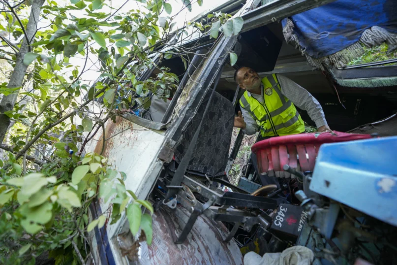 A forensic official inspects a bus that fell into a deep gorge on Sunday after being fired at by suspected militants in Reasi district, Jammu and Kashmir, Monday, June 10, 2024. (AP Photo/Channi Anand)