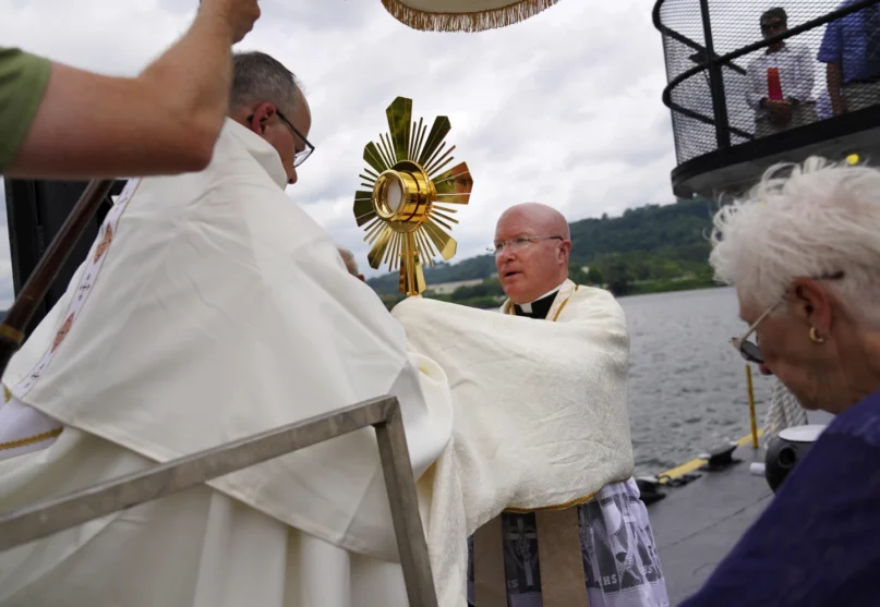 Bishop Edward Lohse, apostolic administrator of the Catholic Diocese of Steubenville, left, hands the Eucharist to the Rev. Roger Landry as they board a boat on the Ohio River as part of the National Eucharistic Pilgrimage, at the Steubenville Marina in Steubenville, Ohio, Sunday, June 23, 2024. (AP
Photo/Jessie Wardarski)