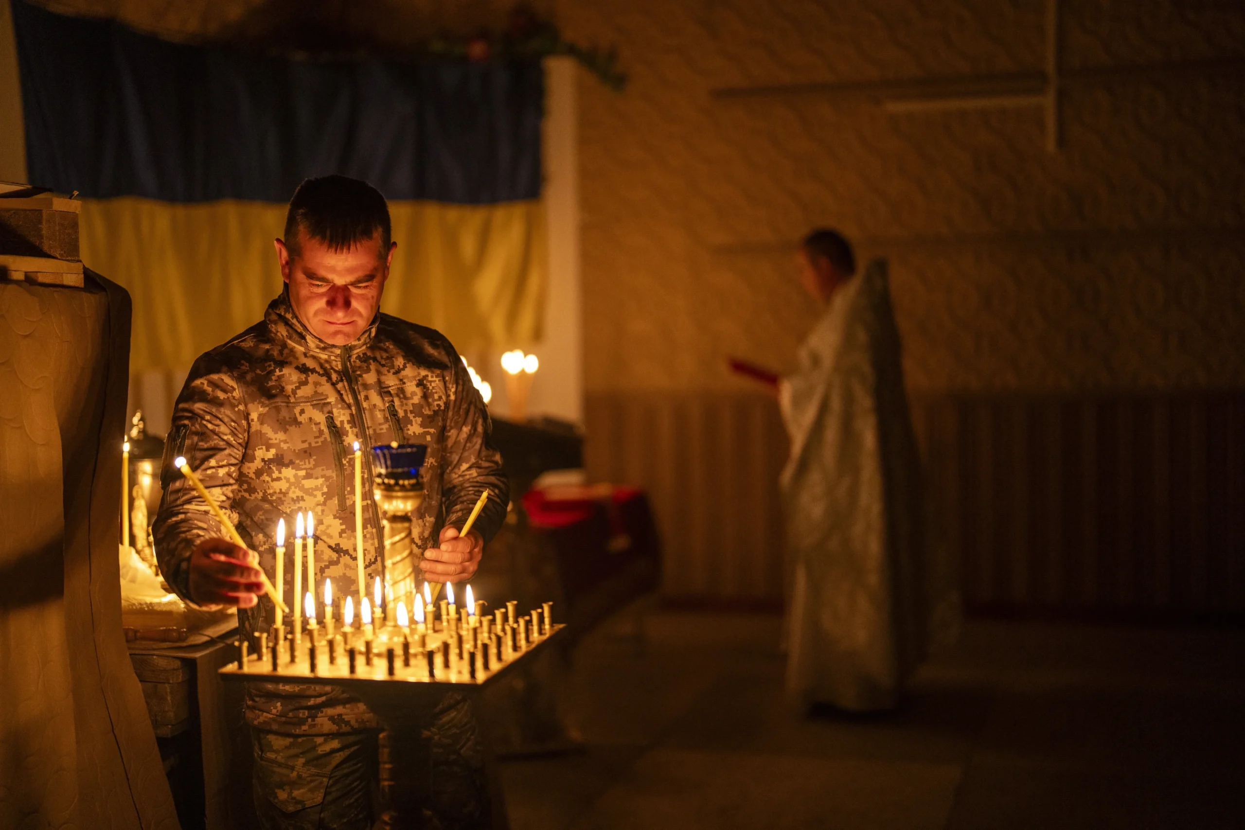 A Ukrainian serviceman of the 72nd Separate Mechanized Brigade, lights candles during a Christian Orthodox Easter religious service, in Donetsk region, Ukraine, Saturday, May 4, 2024. (AP Photo/Francisco Seco)